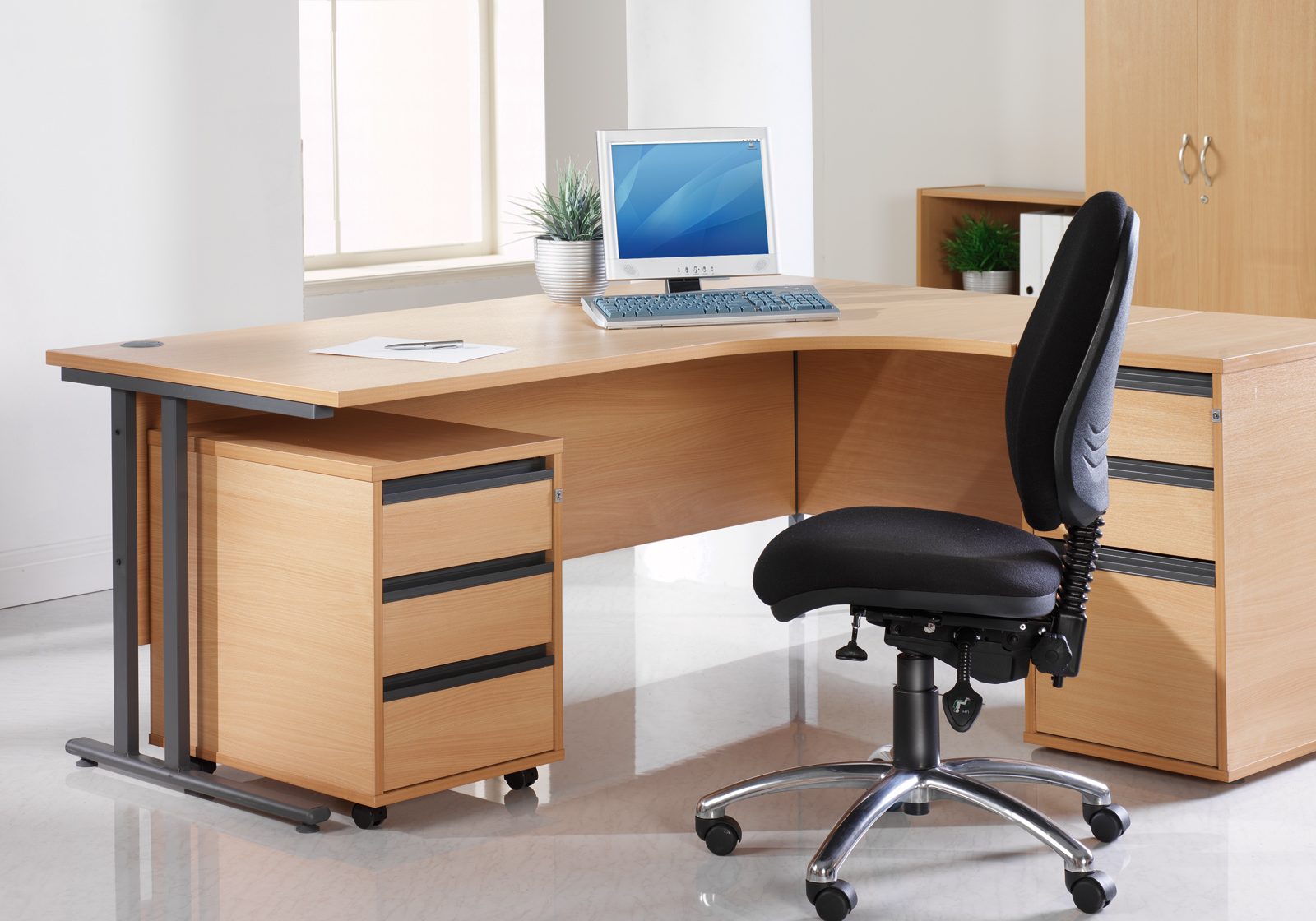 Desk with computer on it and a black swivel chair